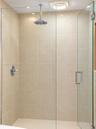 Walk-in shower featuring floor-to-ceiling tile, frameless glass enclosure, polished chrome rainfall showerhead, and a matching temperature control val