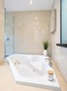 Jetted soaking tub with deck-mounted chrome faucet, recessed ceiling lighting, glass-enclosed shower, and floor-to-ceiling tile surround