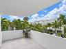 Covered balcony featuring neutral stone-finish tile flooring and a black metal railing
