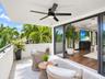 Covered balcony featuring large-format stone tile flooring, a matte black ceiling fan with integrated lighting, and a metal-rail balcony perimeter