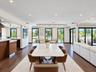 Open-concept interior featuring wood-finish flooring, recessed lighting, expansive glass sliding doors, and a built-in kitchen peninsula with a stone-