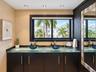 Dual vanity featuring a glass countertop, dark espresso-finish cabinetry, metallic hardware, and two blue glass vessel sinks with modern chrome faucet