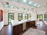 Kitchen featuring a substantial island with stone-surface countertops, dark wood-finish cabinetry, built-in stainless steel dishwasher, track lighting