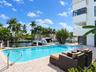 Waterfront swimming pool with paver decking, metal handrails, and direct bulkhead access to a canal