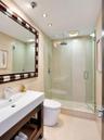 Bathroom featuring a floating vanity with a rectangular sink, walk-in shower with a glass enclosure and rain-style showerhead, recessed lighting, and 