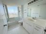 Bathroom featuring a white vanity with integrated countertop sink, full-width wall mirror, shower-tub combination with glass enclosure, and large-form