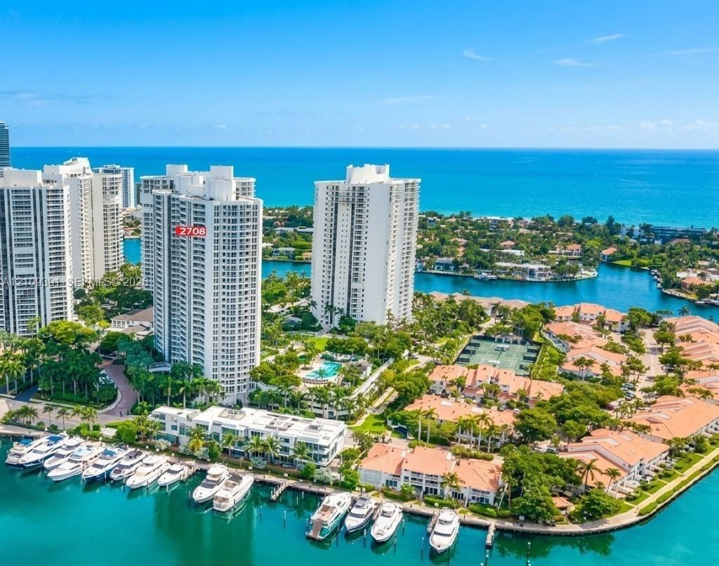 High-rise tower featuring multi-level private balconies, expansive glass windows, and a structured exterior facade, surrounded by established tropical