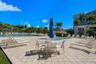 Outdoor swimming pool featuring a paved deck, surrounding palm trees, and structural shade pavilion