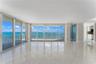 Floor-to-ceiling glass doors, expansive balcony with metal railing, polished tile flooring, and neutral wall finishes