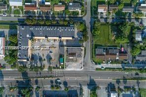Aerial perspective of the subject property featuring a paved parking area, commercial structure, and street frontage