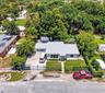 Single-story residence featuring a metal roof, concrete driveway, fenced perimeter, and mature landscaping