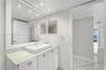 Bathroom featuring a white vanity with a glass countertop, rectangular vessel sink, wall-spanning mirror, recessed lighting, and tile flooring
