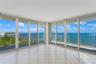 Floor-to-ceiling glass panel walls, wraparound balcony with metal railing, and light-toned ceramic tile flooring