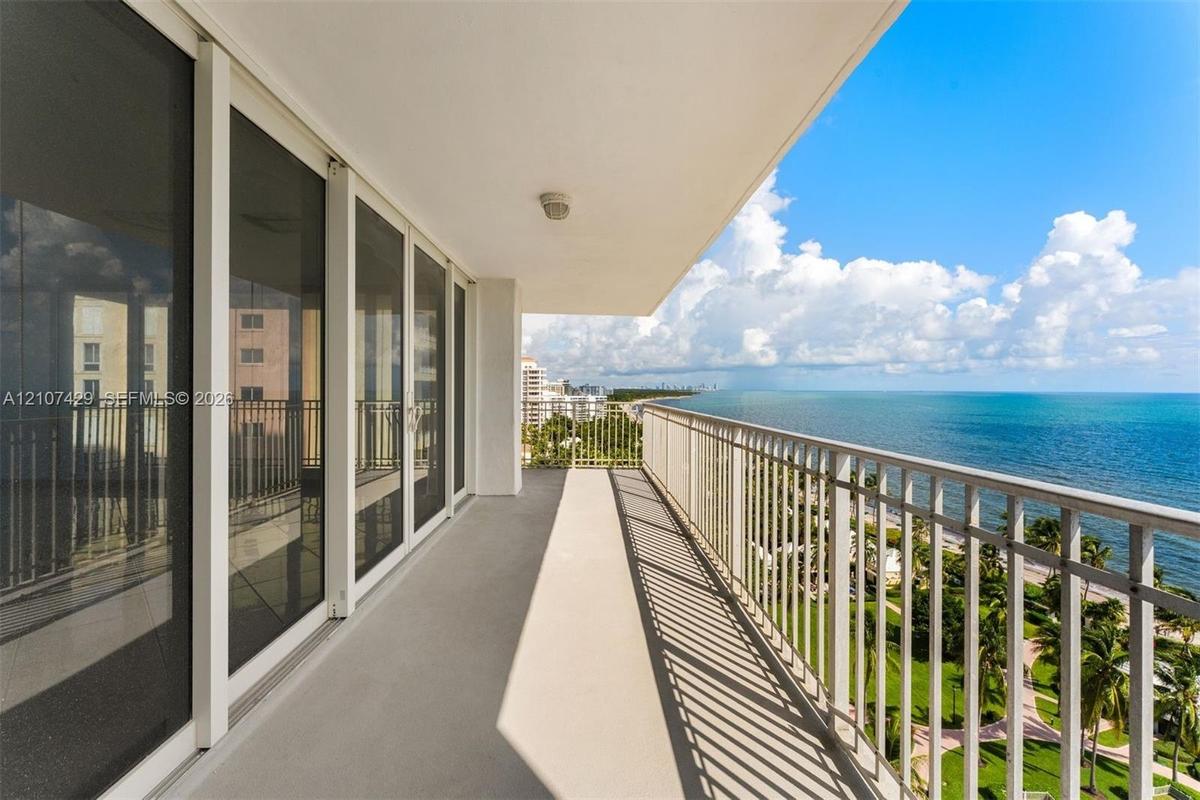 Covered balcony featuring white metal railing, concrete flooring, and full-height sliding glass doors