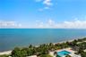 Oceanfront panorama featuring direct water access, a swimming pool, paved sundeck, and lush tropical landscaping