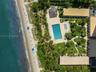 Oceanfront property featuring direct beach access, an expansive rectangular swimming pool, a separate secondary pool, manicured lawns, and established