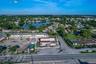 Aerial perspective of a corner commercial property featuring direct street access, a paved parking lot, and proximity to a regional waterway