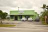 Commercial property featuring a concrete exterior, metal roof canopy, and asphalt parking area
