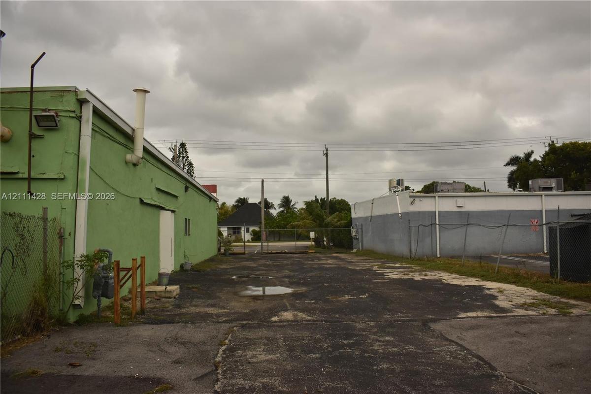 Paved exterior lot featuring metal-sided structures and chain-link fencing