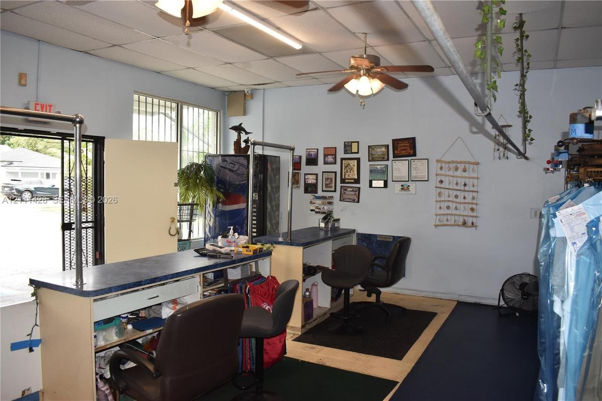 Interior space featuring a suspended drop ceiling, overhead ceiling fan with light fixture, metal-framed service counter with laminate surface, and se