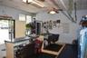 Interior space featuring a suspended drop ceiling, overhead ceiling fan with light fixture, metal-framed service counter with laminate surface, and se