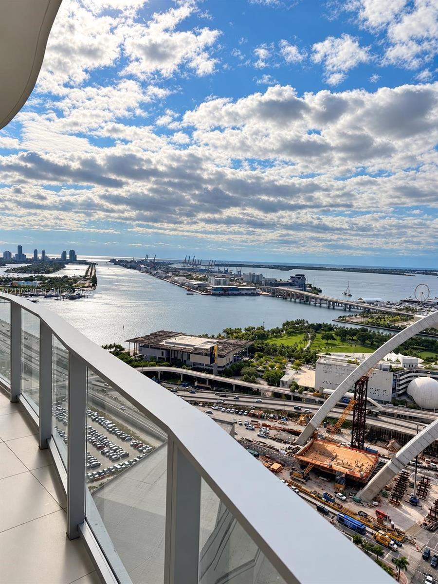 Private balcony with glass panel railing and panoramic waterfront and city skyline scenery