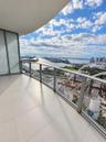 Covered balcony featuring large-format porcelain tile flooring and a glass panel railing
