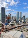 Panoramic urban landscape featuring a high-rise skyline, architectural arched bridge infrastructure, and elevated highway networks