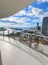 Covered balcony featuring large-format tile flooring and a glass railing system with metal framing