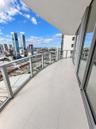 Covered private balcony featuring large-format tile flooring, a glass-panel railing, and floor-to-ceiling glass sliding doors