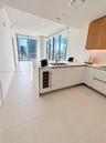 Kitchen featuring custom cabinetry with white lower and wood-finish upper units, integrated wine refrigerator, quartz-surface countertops, and expansi