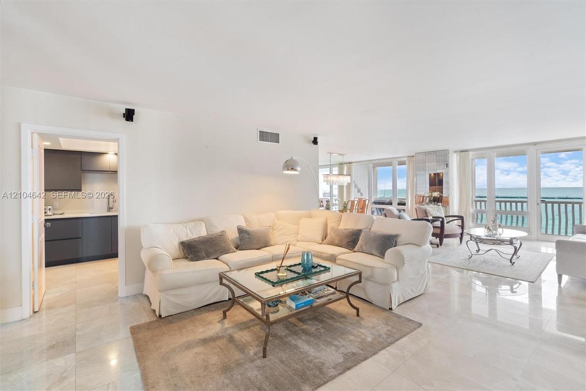 Open-concept living space featuring polished tile flooring, floor-to-ceiling windows, and direct access to a balcony with ocean exposure