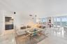 Open-concept living space featuring polished tile flooring, floor-to-ceiling windows, and direct access to a balcony with ocean exposure