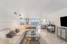 Living area featuring polished stone tile flooring, floor-to-ceiling glass panel doors, and a decorative wall-mounted mirror