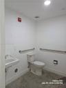 Wall-mounted porcelain sink with chrome faucet, floor-mounted toilet, and stainless steel grab bars