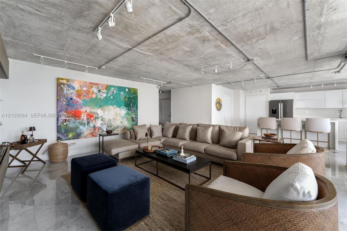 Industrial-inspired kitchen featuring an exposed concrete ceiling with surface-mounted conduit, high-gloss white cabinetry, stainless steel appliances