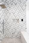 Glass enclosed walk in steam shower with geometric patterned tile and bench seating. Newly remodeled