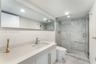 Exposed concrete ceiling with industrial-style track lighting, large-format tile flooring, and custom wall-mounted wood cabinetry with integrated shel