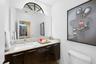 Floating vanity with dark wood-finish cabinetry, stone countertop, integrated rectangular sink, and large frameless mirror