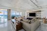 Contemporary kitchen featuring high-gloss white cabinetry, a waterfall-edge quartz island, stainless steel appliances, exposed concrete ceiling with i