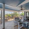 Screened-in porch featuring large-format tile flooring, blue painted ceiling, integrated ceiling fan, and extensive screened walls