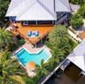 Aerial perspective featuring a multi-level wood deck, swimming pool with paver surround, and private boat dock with metal roof