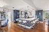 Kitchen featuring custom navy and white cabinetry, stone-finish countertops, multi-tonal mosaic tile breakfast bar, pendant lighting, and wood-finish 