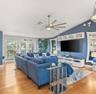 Vaulted ceiling featuring a multi-blade ceiling fan, expansive wood-finish flooring, and built-in upper wall cabinetry