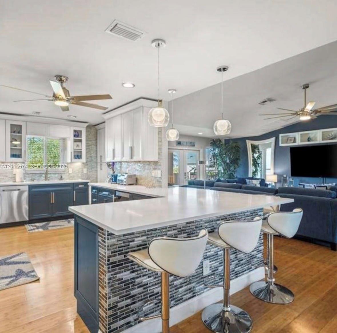 Kitchen featuring white shaker-style cabinetry, a quartz-topped island with mosaic tile inlay, glass globe pendant lighting, stainless steel appliance