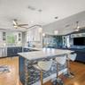 Kitchen featuring white shaker-style cabinetry, a quartz-topped island with mosaic tile inlay, glass globe pendant lighting, stainless steel appliance