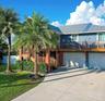 Two-story exterior featuring a metal roof, wraparound wooden deck, dual-bay garage, and concrete driveway