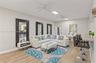 Living area featuring wood-finish flooring, two ceiling fans, recessed lighting, and three wall-mounted, dark-framed mirrors