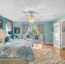 Crystal-style chandelier with a central ceiling fan, wood-finish flooring, and glass-paneled entry door