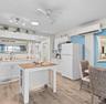 Kitchen featuring white cabinetry, stone-finish countertops, wood-finish flooring, a ceiling fan, and a wall-mounted ductless air conditioning unit